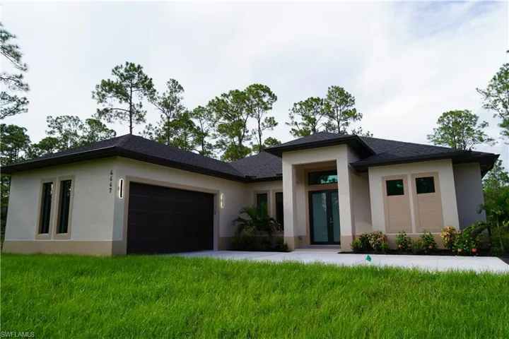 Prairie-style house featuring stucco siding, a garage, a front lawn, and driveway
