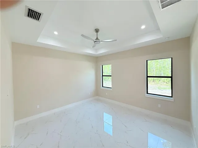 Unfurnished room featuring light marble finish flooring, a tray ceiling, ceiling fan, and recessed lighting