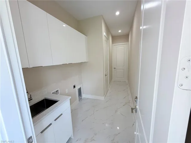 Laundry room featuring recessed lighting, light marble finish flooring, hookup for a washing machine, cabinet space, and hookup for an electric dryer
