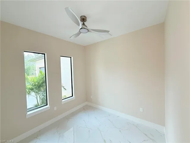 Unfurnished room featuring light marble finish floors and a ceiling fan