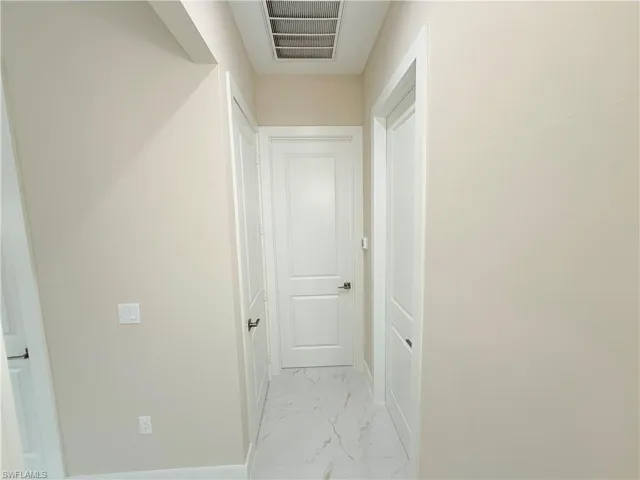 Hallway featuring light marble finish flooring and baseboards