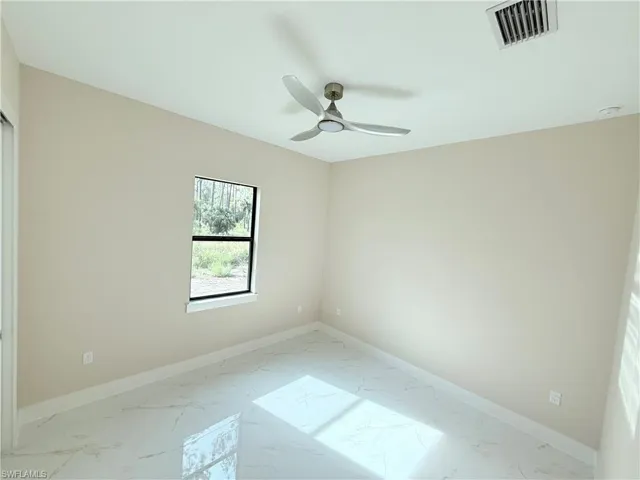 Unfurnished room with marble look tile flooring and a ceiling fan