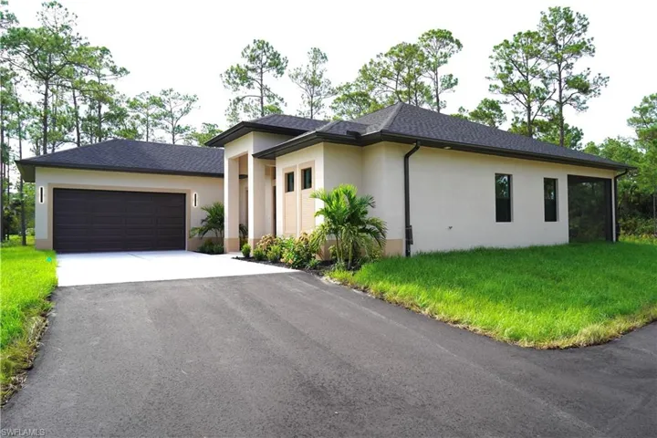 View of front of home with driveway, stucco siding, an attached garage, and a front yard