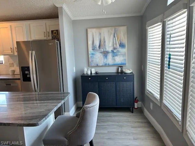 Dining space with a textured ceiling, light wood-type flooring, ceiling fan, and crown molding