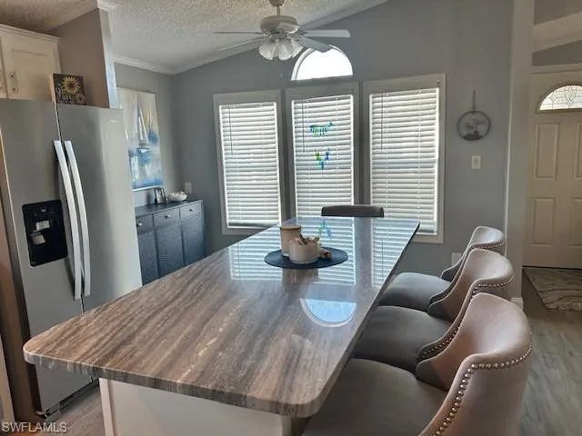 Dining area with light wood-style floors, ceiling fan, crown molding, and healthy amount of natural light
