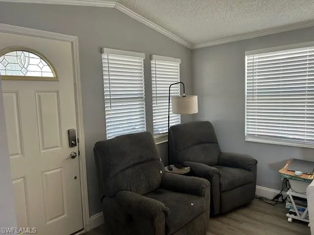 Living area with wood finished floors and ornamental molding
