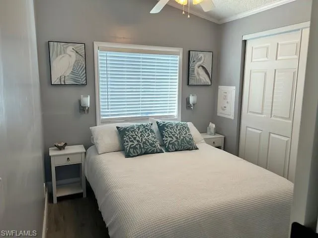 Bedroom featuring a ceiling fan, ornamental molding, dark wood finished floors, and a closet