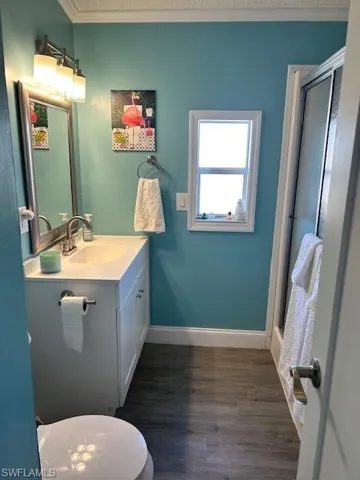 Bathroom featuring a shower stall, vanity, dark wood finished floors, and crown molding