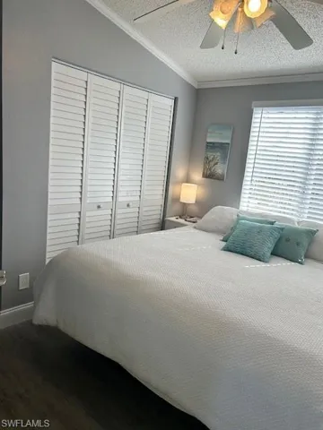 Bedroom with crown molding, finished floors, ceiling fan, and a closet