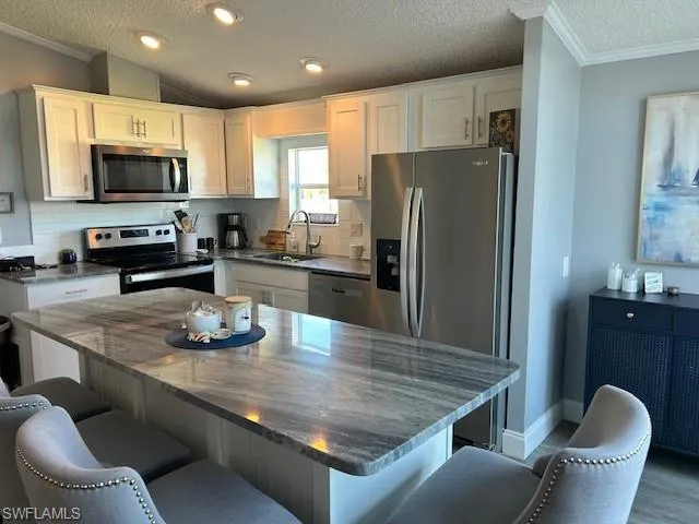 Kitchen featuring crown molding, stainless steel appliances, decorative backsplash, a center island, and a breakfast bar