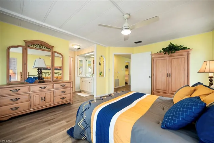 Bedroom featuring light wood-style flooring, ceiling fan, and ensuite bathroom