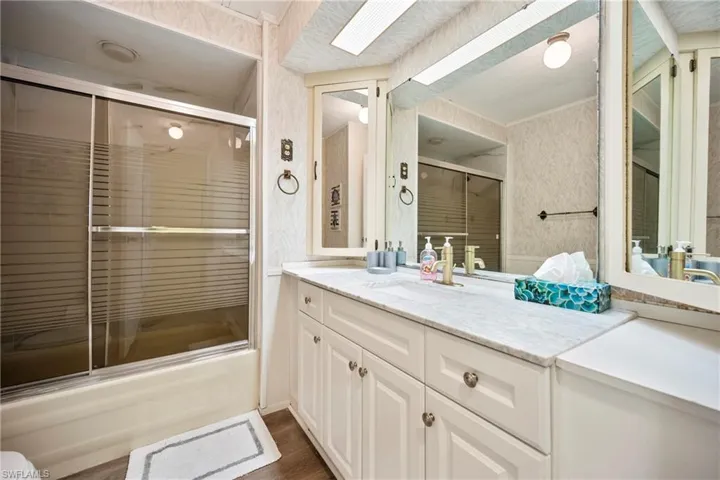 Bathroom featuring vanity and combined bath / shower with glass door