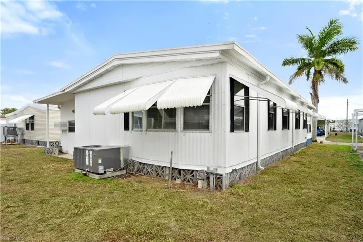 View of property exterior with a lawn and a central air condition unit