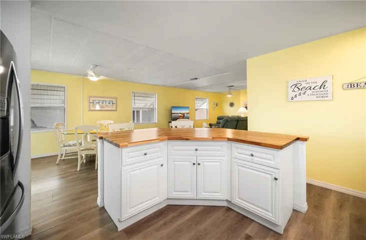 Kitchen featuring butcher block countertops, stainless steel refrigerator with ice dispenser, white cabinetry, and dark wood-style floors