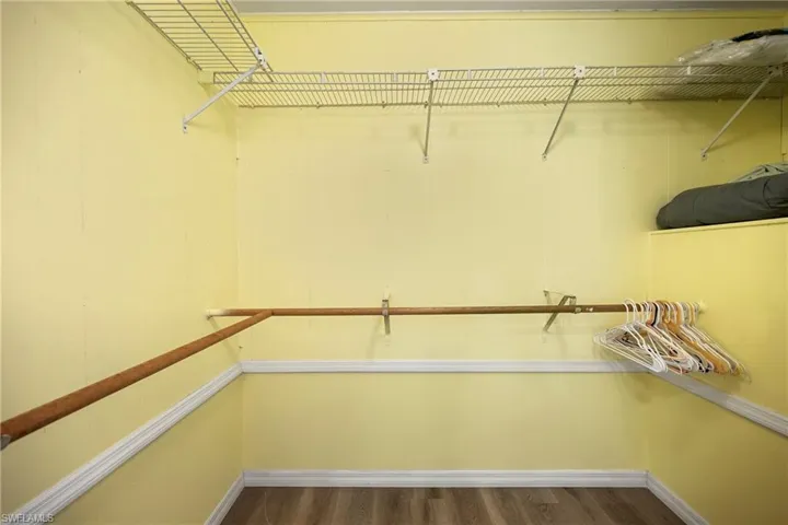 Walk in closet with dark wood-style flooring