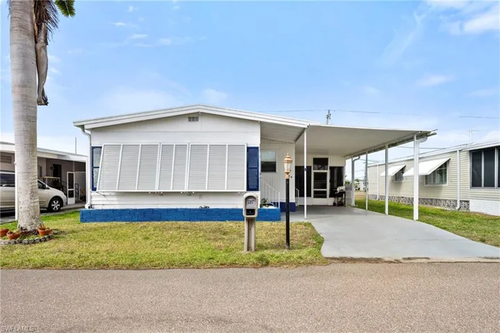 View of front of home featuring a carport, a front lawn, and driveway
