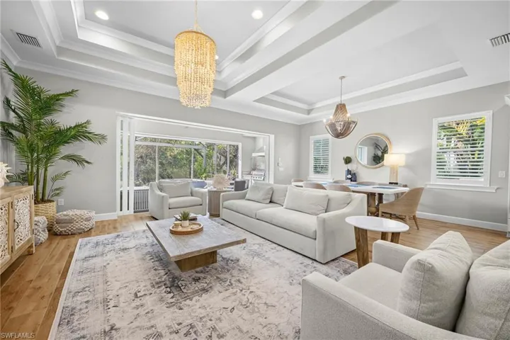 Spacious living area featuring a tray ceiling with recessed lighting and a large decorative chandelier