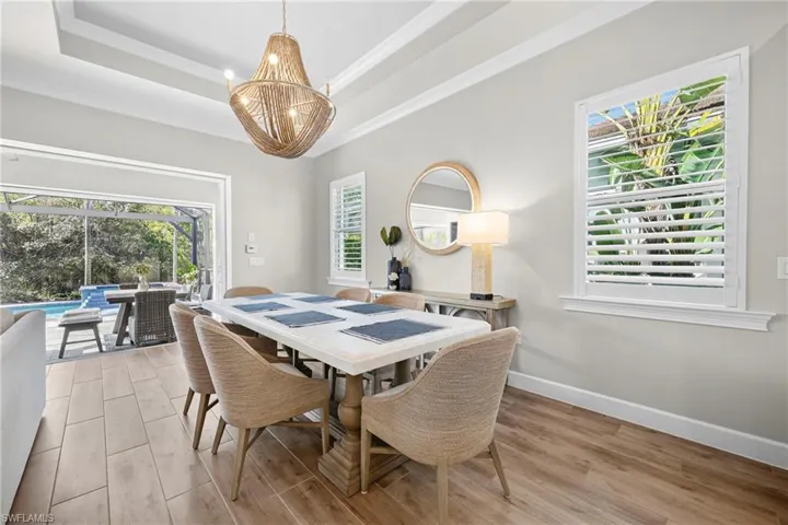 Dining area with wood-finish flooring, coffered ceiling, and a large chandelier