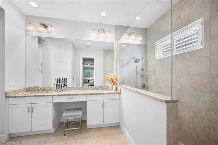 Spacious bathroom featuring a dual vanity with granite countertops, white cabinetry, and a dedicated makeup area