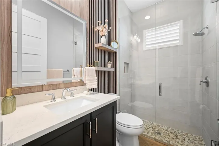 Modern bathroom featuring a dark wood vanity with a white countertop and undermount sink