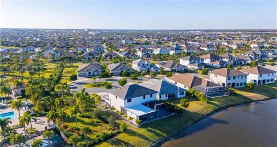 Expansive residential development featuring numerous homes, a community pool, mature landscaping, and waterfront properties