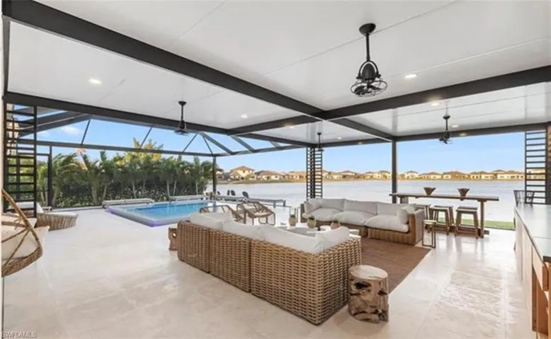 Expansive screened lanai with a rectangular pool, water views, recessed lighting, and ceiling fans