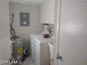 Laundry area featuring independent washer and dryer, cabinet space, and electric panel