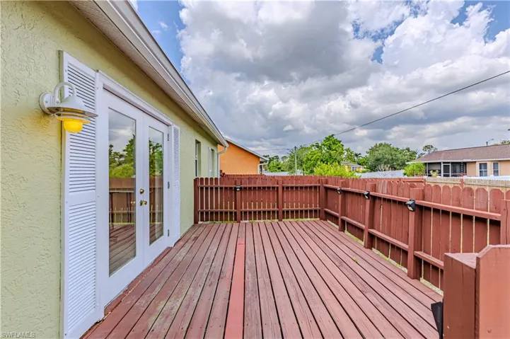 Wooden deck featuring french doors and a fenced backyard