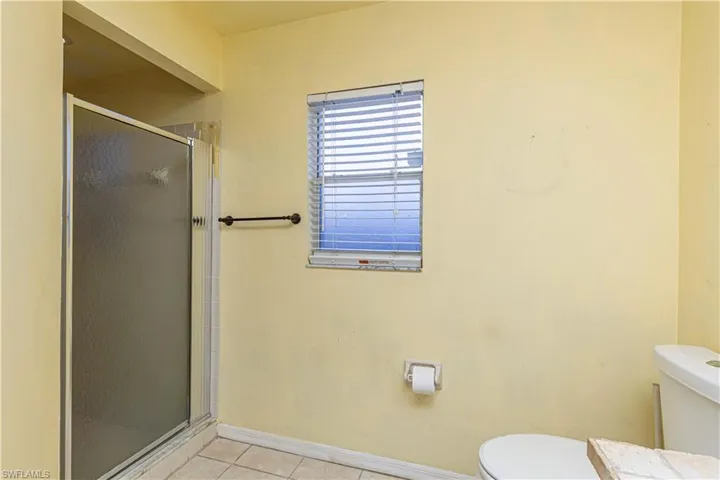 Full bathroom with toilet, tile patterned flooring, a shower stall, and baseboards