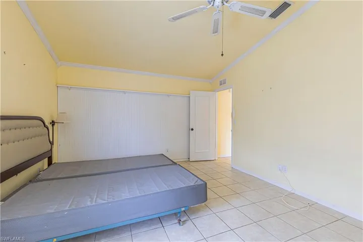 Unfurnished bedroom with light tile patterned floors, ornamental molding, and ceiling fan