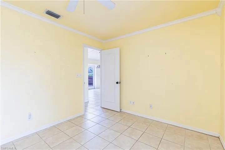 Unfurnished room featuring crown molding, a ceiling fan, light tile patterned flooring, and baseboards