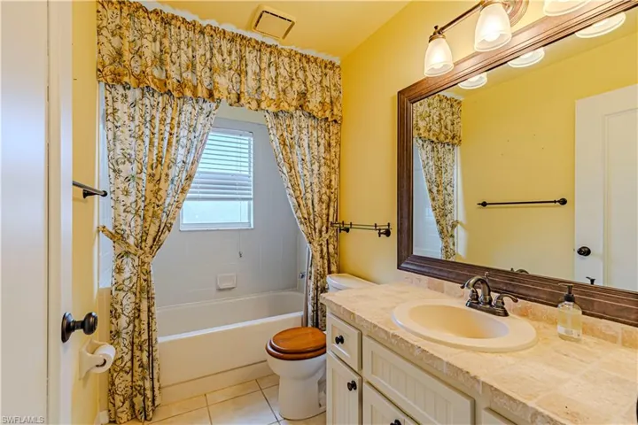 Full bath featuring vanity, toilet, shower / tub combo, and tile patterned floors