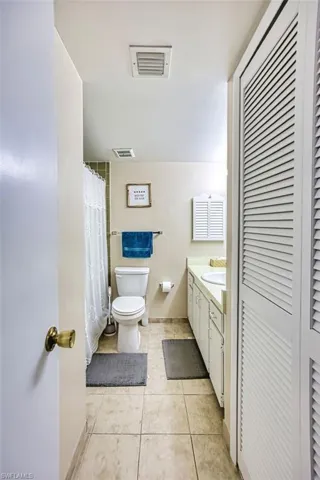 Bathroom featuring a closet, vanity, curtained shower, and light tile patterned floors