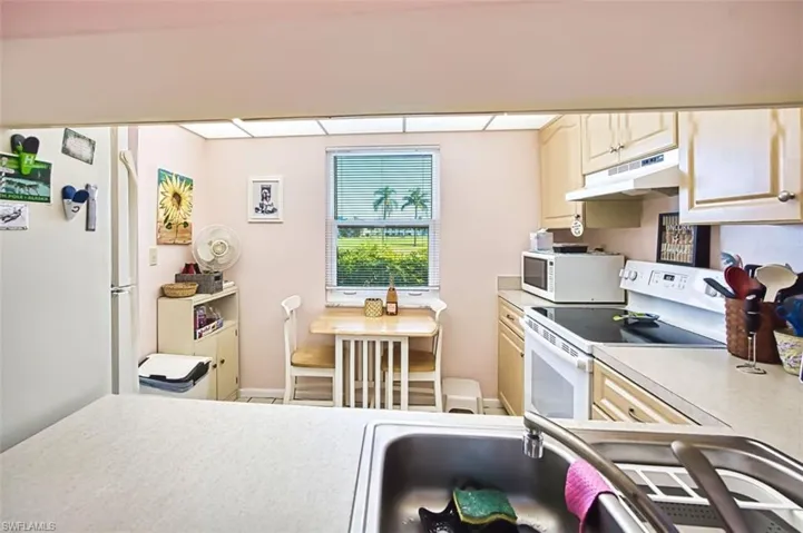 Kitchen featuring white appliances, light countertops, and light wood finish cabinetry