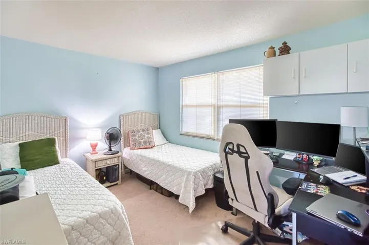 Bedroom with light colored carpet, a desk, and a textured ceiling