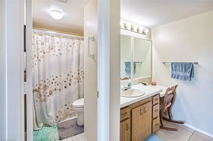 Full bathroom featuring a shower with shower curtain, vanity, and light tile patterned floors