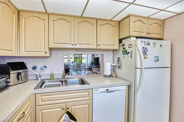 Kitchen featuring light wood finish cabinetry, white appliances, and light countertops
