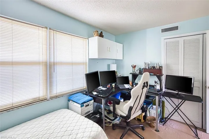 Bedroom featuring an office area, a textured ceiling, and a closet