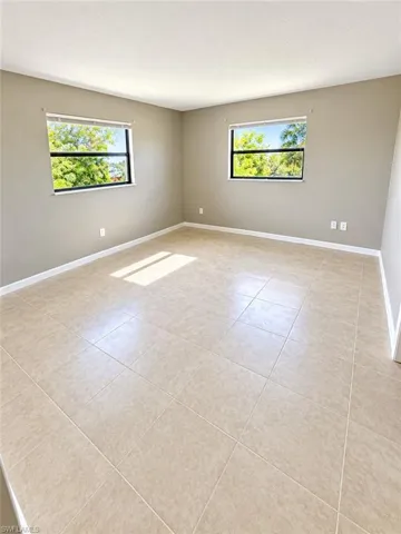Neutral wall color, two windows with exterior scenery, and tiled flooring