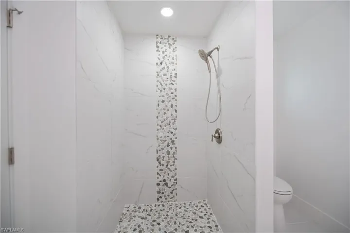 Bathroom with a marble finish shower and toilet