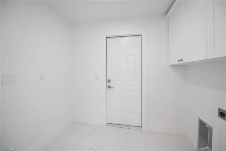 Laundry room with light marble finish flooring, hookup for an electric dryer, and cabinet space