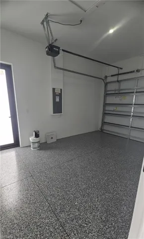 Spacious garage with an epoxy-coated flooring, a paneled garage door, and an automatic garage door opener