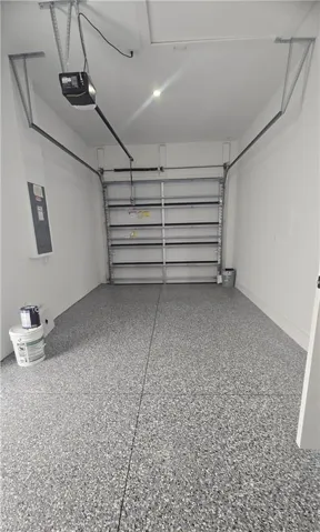 Garage interior featuring a speckled epoxy floor coating, white painted walls, and a visible garage door opener mechanism
