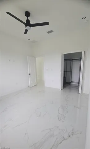 Spacious interior room featuring large format tile flooring, a modern black ceiling fan, and recessed lighting