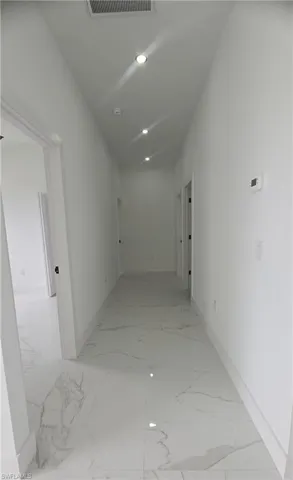 Bright hallway featuring polished tile flooring, recessed lighting, white walls, and white baseboards