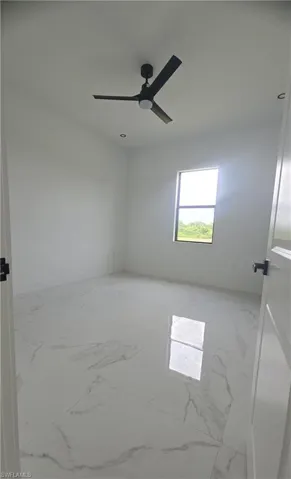 Spacious room featuring large format porcelain tile flooring, a modern black ceiling fan, recessed lighting, white walls, and a window providing natural light