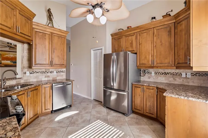 Kitchen with sink, backsplash, light tile patterned floors, ceiling fan, and stainless steel appliances