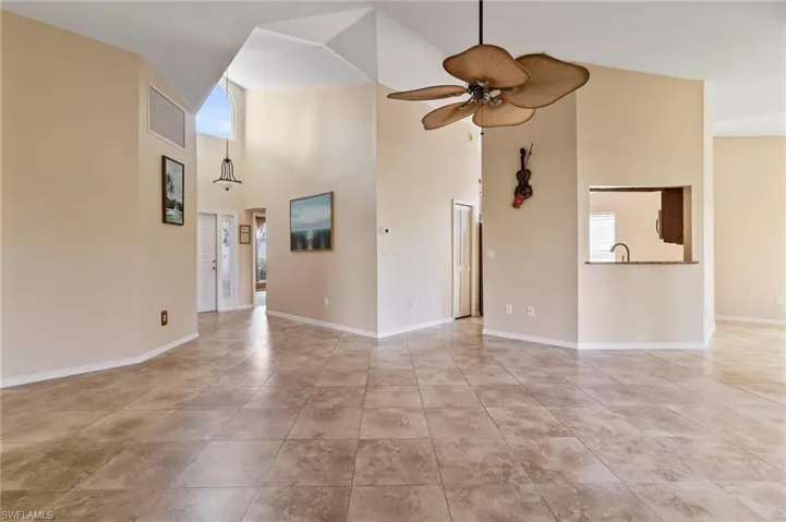 living room featuring a high ceiling, light tile patterned flooring, and ceiling fan