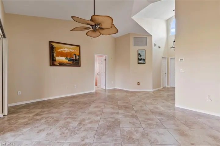 Tiled living room with a high ceiling and ceiling fan