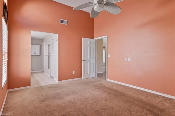 Primary bedroom featuring a towering ceiling, light colored carpet, ceiling fan, and a closet